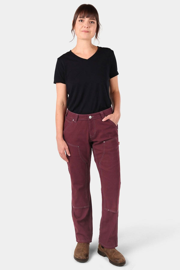 Woman wearing Dovetail Workwear's Anna Taskpant in Elderberry Canvas, a mid-rise relaxed-fit work pant with visible Hip Slot™ Tool loop and multiple pockets, paired with a black v-neck tee
