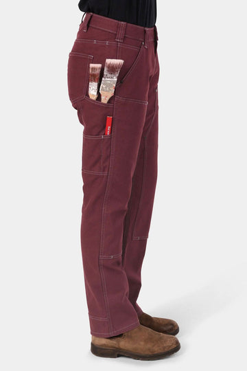 Side view of a woman wearing the Anna Taskpant in Elderberry Canvas by Dovetail Workwear, showcasing multiple tool pockets and relaxed-fit silhouette with straight leg