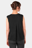Back view of a woman wearing the Dovetail Workwear Bellows Work Tank Top in Black, showing the longer back length and center back pleat detail