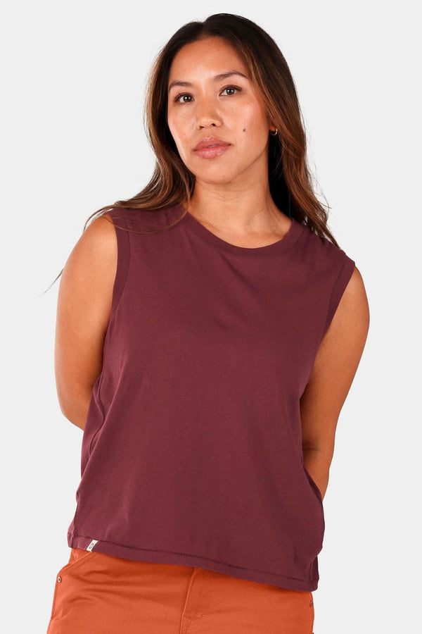 Elderberry Bellows Work Tank Top by Dovetail Workwear worn by a woman, featuring a loose fit and breathable cotton design in a deep maroon color