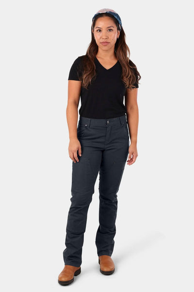 Woman wearing Dovetail Workwear's Britt X Ultralight Work Pant in Navy Ripstop with black v-neck tee and brown boots, front view