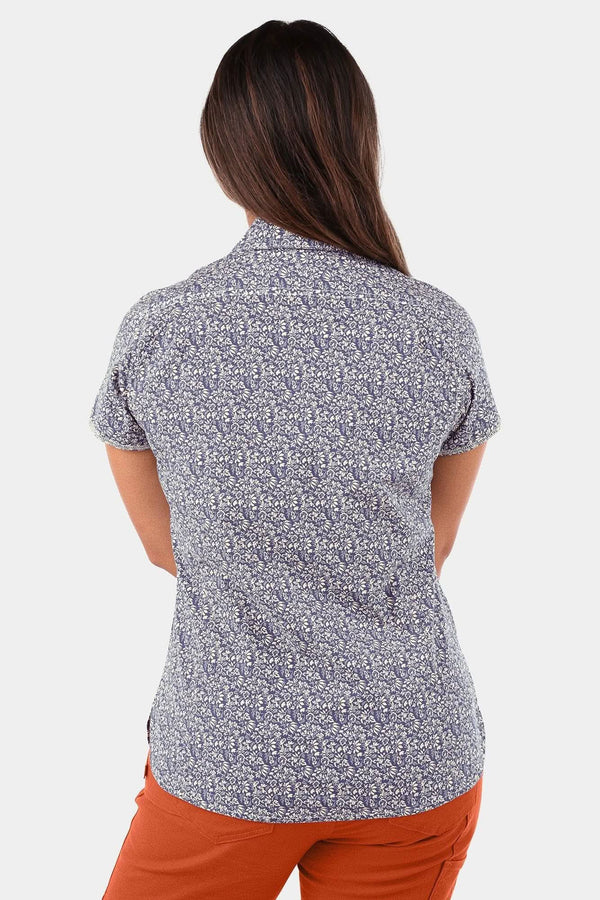 Back view of a woman wearing the Dovetail Workwear Carver Work Shirt in Navy with a paisley print and short sleeves, paired with orange pants