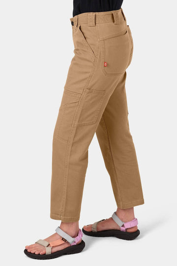Side view of a woman wearing Dovetail Workwear's Range Crop Pant in Sawdust Brown, showcasing the cropped length, bellowed front pockets, and relaxed leg fit