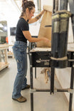 Woman wearing Dovetail Workwear Day Construct Work Pant in Vintage Blue Stretch Denim, demonstrating the relaxed leg fit and mid-rise waist while working in a studio setting