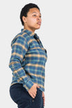 Side view of a woman wearing the Givens Work Shirt in Stretch Flannel in Coffee and Vintage Blue Plaid by Dovetail Workwear, featuring a plaid pattern, chest pocket, and cuff tabs