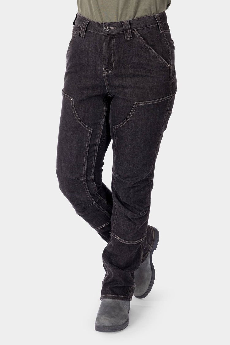 Woman wearing Dovetail Workwear Old School High Rise Graphene Denim Pant in Heather Black with visible crotch gusset, knee pad slots, and reinforced construction, paired with gray work boots