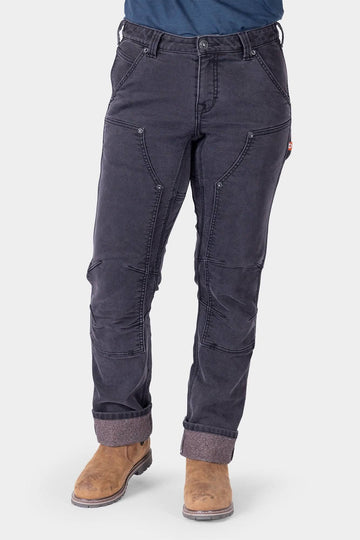 Britt Utility HOTSWAP™ Pant in Black Thermal Denim by Dovetail Workwear, shown on a woman wearing tan boots, featuring cargo-style pockets and Tough Cuff™ rolled cuffs