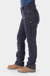 Side view of a woman wearing Dovetail Workwear's Britt Utility HOTSWAP™ Pant in Black Thermal Denim, showing the straight leg fit, tool loop, and cargo-style pockets paired with tan boots