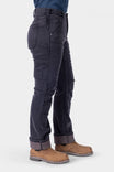 Side view of a woman wearing Dovetail Workwear's Britt Utility HOTSWAP™ Pant in Black Thermal Denim, featuring multiple cargo pockets and a Tough Cuff™, paired with brown boots