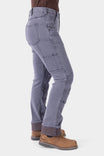 Side view of a woman wearing Dovetail Workwear's Britt Utility HOTSWAP™ Pant in Grey Thermal Denim, showcasing cargo-style pockets, tool loop, and thermal lining cuffed at the ankle