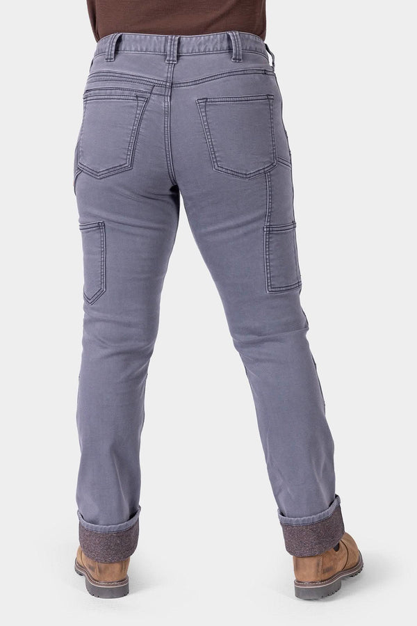 Back view of a woman wearing Dovetail Workwear's Britt Utility HOTSWAP™ Pant in Grey Thermal Denim, featuring cargo-style pockets, tool loops, and Tough Cuff™ with thermal lining