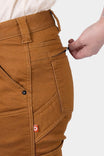 Close-up detail of the Britt Utility HOTSWAP™ Pant in Saddle Brown Thermal Denim by Dovetail Workwear, showing the tool loop and Hip Slot™ zip pocket being accessed by a woman's hand