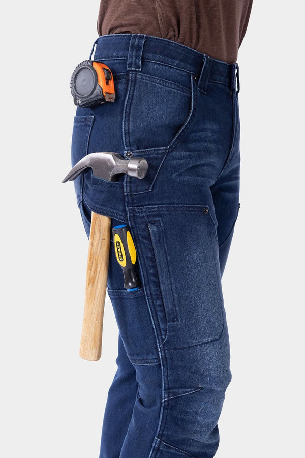 Dovetail Workwear Britt X Graphene Denim Pant in indigo worn by a woman with tools in cargo pockets and belt loops, showing durability and functionality