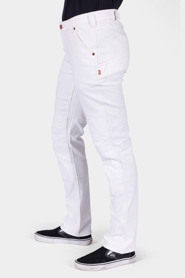 Side view of a woman wearing the GO TO™ Stretch Canvas Work Pant in Painter's White by Dovetail Workwear, showcasing the articulated knee and nested pockets with black slip-on sneakers