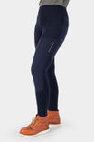 Side view of a woman wearing Dovetail Workwear's Field Utility Legging in Black, featuring visible front pockets and nylon reinforcements, paired with brown lace-up boots