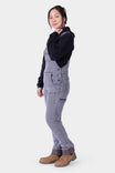 Side view of a woman wearing Dovetail Workwear's Freshley HOTSWAP™ Drop Seat Thermal Denim Overalls in Grey with a black hoodie and brown boots