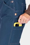 Detail shot of the Atlantic Blue GO TO™ Stretch Canvas Overalls by Dovetail Workwear, highlighting the reinforced knee and phone pocket with a yellow device visible