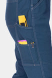 Close-up of GO TO™ Stretch Canvas Overalls in Atlantic Blue by Dovetail Workwear, highlighting nested pockets with yellow and pink items stored inside and reinforced knee construction