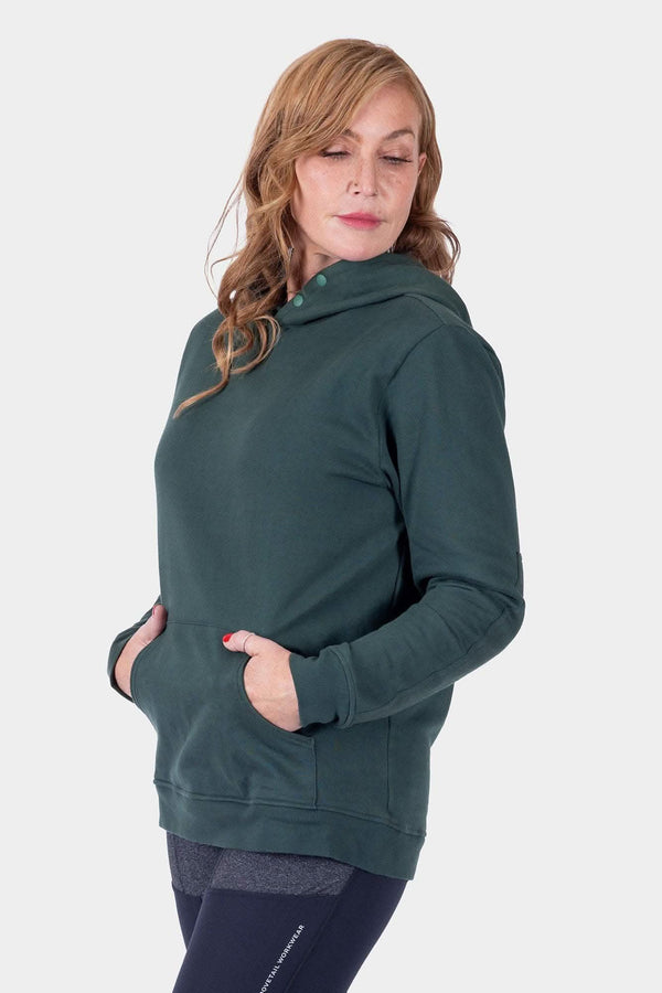 Back view of a woman wearing the Dovetail Workwear GO TO™ Hoodie in Lodge Green, featuring a relaxed fit, kangaroo pocket, and snap neck closure