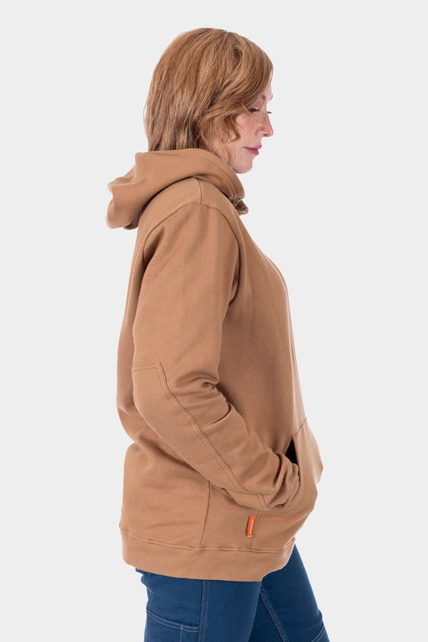 Side view of a woman wearing the Saddle Brown GO TO™ Hoodie by Dovetail Workwear, showcasing the relaxed fit, kangaroo pocket, and reinforced elbows.
