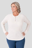 Oatmeal Honed Long Sleeve Thermal Henley by Dovetail Workwear worn by a woman, featuring a waffle knit thermal base layer with button front placket and thumbholes, paired with navy pants