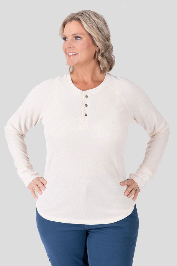 Oatmeal Honed Long Sleeve Thermal Henley by Dovetail Workwear worn by a woman, featuring a waffle knit thermal base layer with button front placket and thumbholes, paired with navy pants