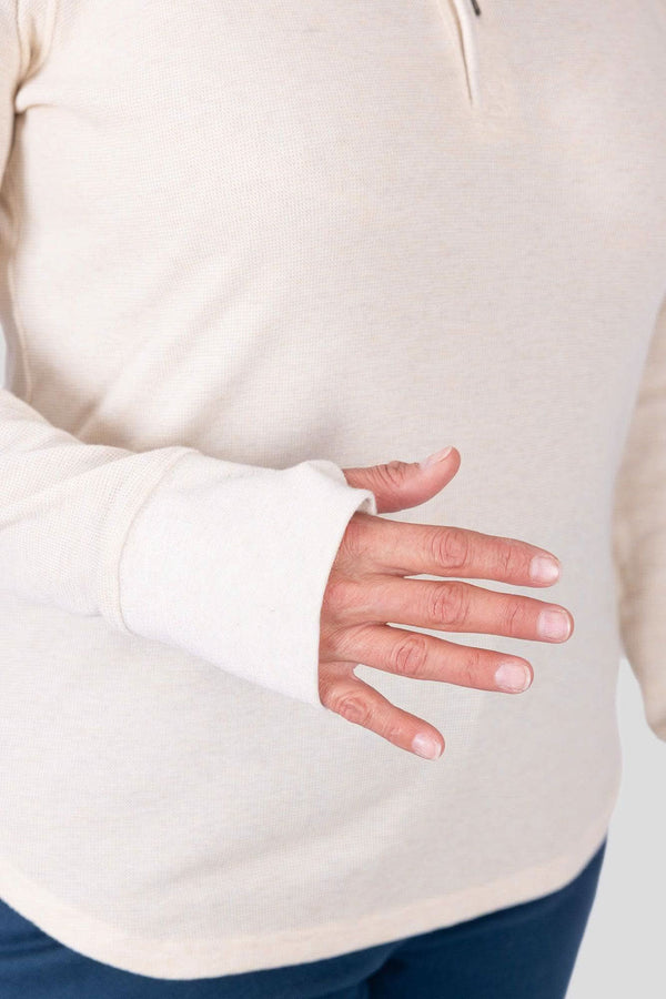 Close-up of a woman wearing the Dovetail Workwear Honed Long Sleeve Thermal Henley in Oatmeal, showing the thumbhole detail and waffle knit texture