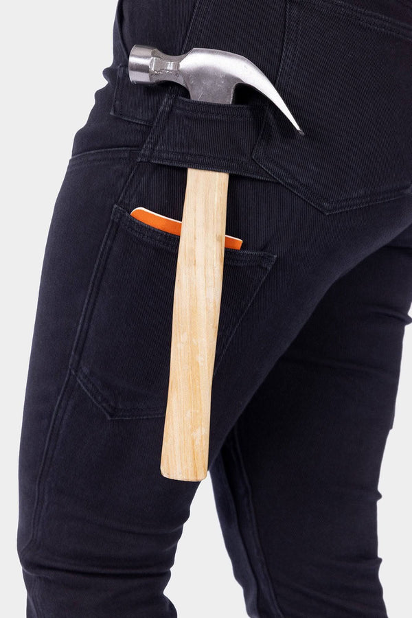 Detail shot of Dovetail Workwear's Maven X Graphene Denim Pant in Black, highlighting the tool loop and reinforced front pocket on a woman wearing work pants