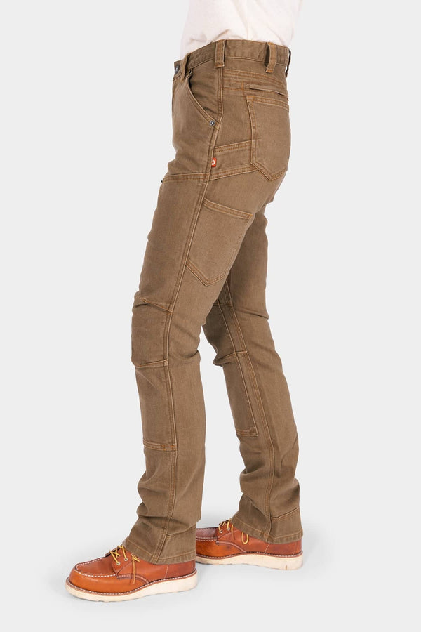 Side view of a woman wearing Dovetail Workwear's Old School High Rise Work Pant in Beechwood Brown denim, showcasing the straight-leg silhouette and tool loop paired with orange work boots