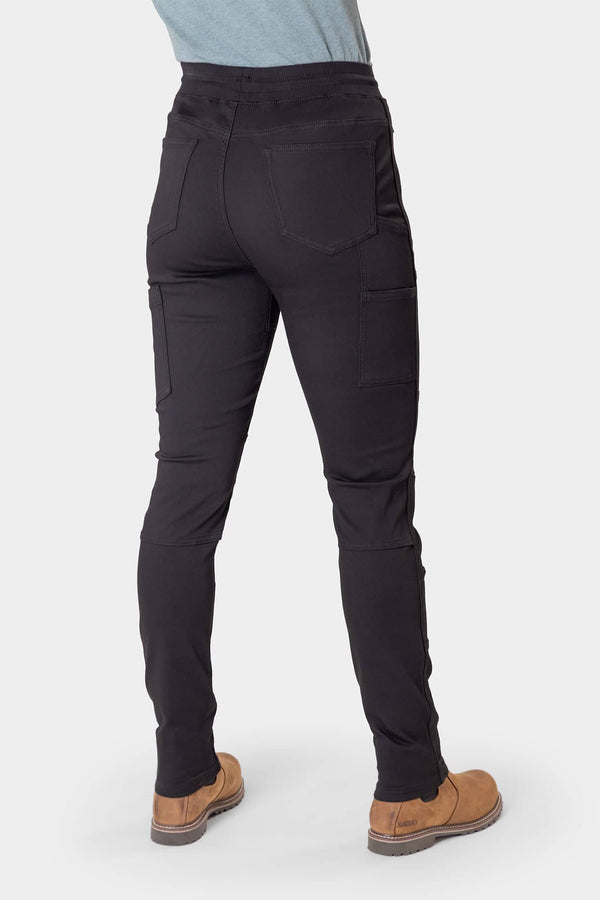 Back view of a woman wearing the Dovetail Workwear Christa X DIY Pant in Black Performance Modal, showcasing the high-rise waistband, reinforced knees, and nested side pockets