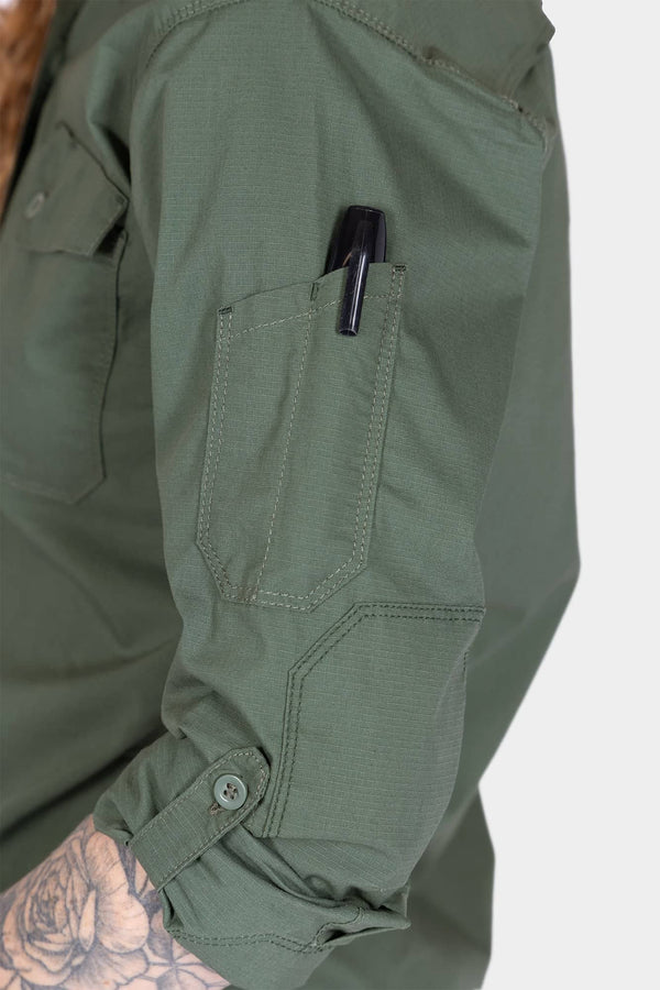 Detail view of the Dovetail Workwear AJ COOLSWAP™ Work Shirt in Aventurine Green showing a buttoned chest pocket with pen holder and reinforced elbow on a woman's arm