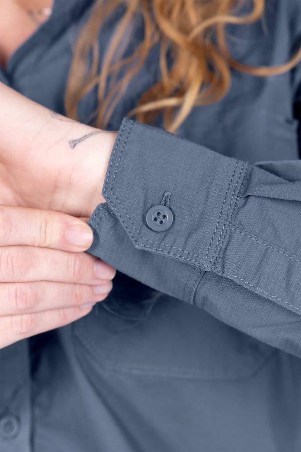 Close-up detail of the chest pocket and hidden snap closure on the Dovetail Workwear AJ COOLSWAP™ Work Shirt in Dovetail Blue, worn by a woman