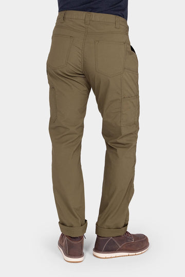 Back view of a woman wearing the Dovetail Workwear Anna Ultralight Trail Pant in Kelp Green Ripstop, showing nested pockets, reinforced knees, and rolled cuffs