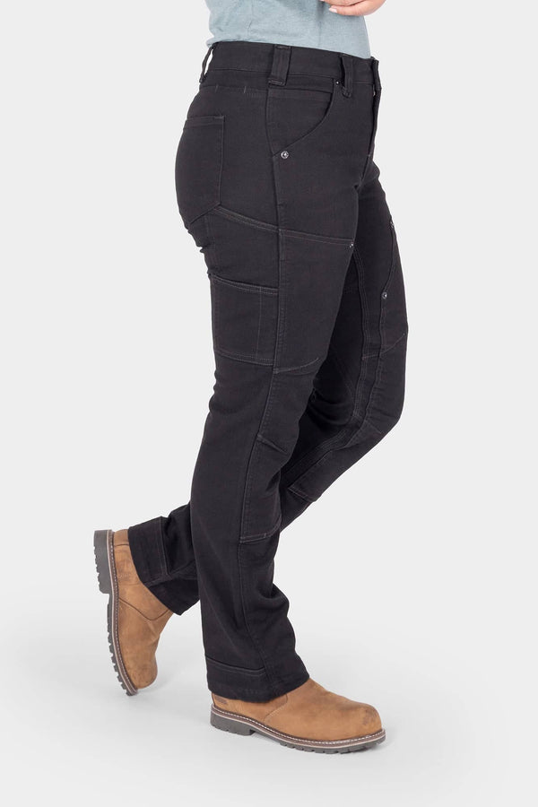 Side view of a woman wearing Dovetail Workwear's Britt Utility Pant in No Fade Black Canvas, featuring nested pockets, reinforced knees, and a straight leg silhouette