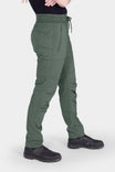 Side view of a woman wearing Dovetail Workwear's Christa X COOLSWAP™ Pant in Aventurine Green, showcasing the high-rise waistband, nested side pockets, and slim leg silhouette