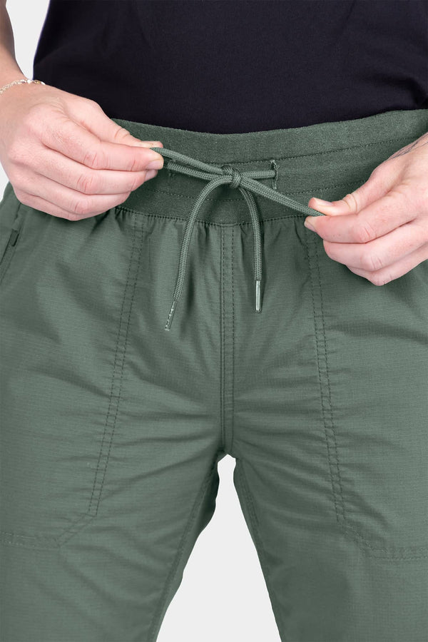 Detail of the drawcord and EZWaist™ waistband on the Christa X COOLSWAP™ Pant in Aventurine Green, shown being adjusted by a woman