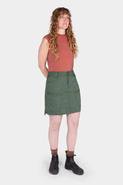 Aventurine Green Compass COOLSWAP™ Cargo Skort by Dovetail Workwear shown on a woman with long curly hair, featuring visible cargo pockets and a high-rise waistband, paired with black boots