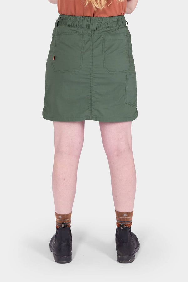 Back view of a woman wearing the Compass COOLSWAP™ Cargo Skort in Aventurine Green by Dovetail Workwear, showing bellowed zip cargo pockets and high-rise waistband