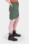 Side view of a woman wearing the Aventurine Green Compass COOLSWAP™ Cargo Skort by Dovetail Workwear, showing the 17.5" length and bellowed zip cargo pockets