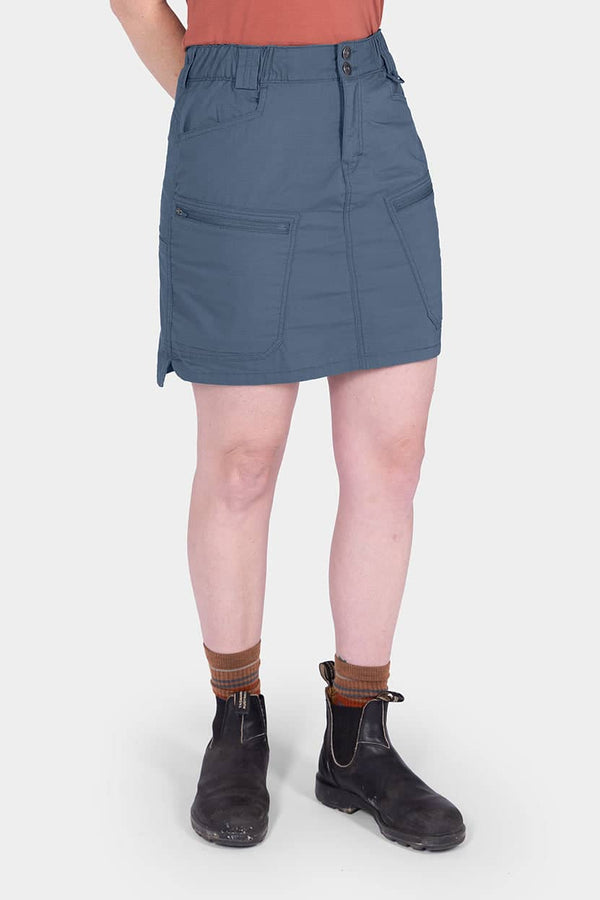 Back view of a woman wearing the Dovetail Workwear Compass COOLSWAP™ Cargo Skort in Dovetail Blue, showcasing bellowed zip cargo pockets and reinforced front pockets.
