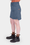 Side view of a woman wearing the Dovetail Workwear Compass COOLSWAP™ Cargo Skort in Dovetail Blue, showing cargo pockets and stretch mesh undershorts