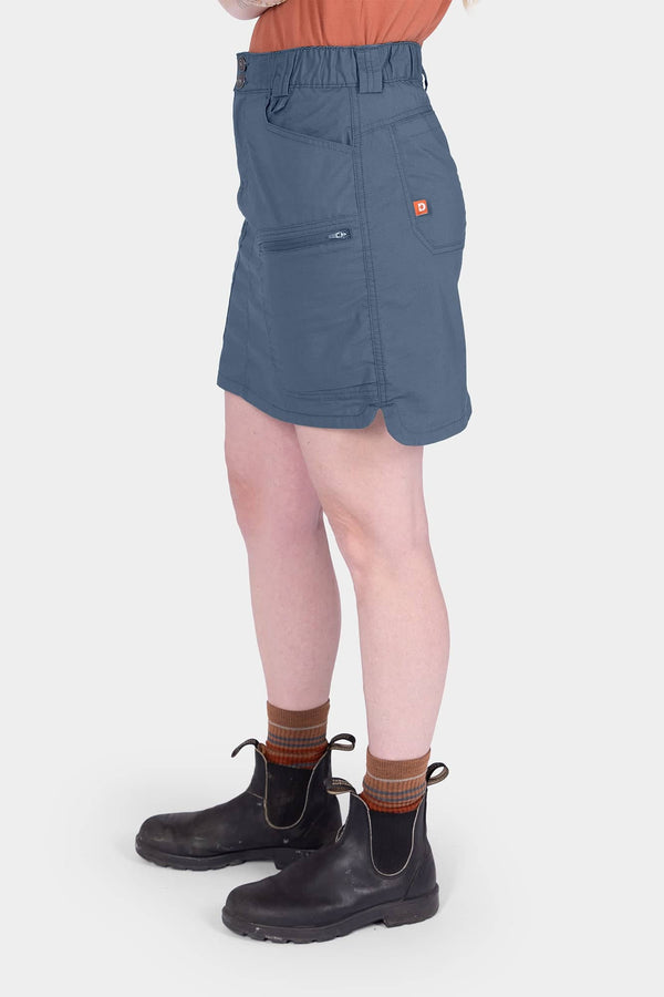 Side view of a woman wearing the Dovetail Workwear Compass COOLSWAP™ Cargo Skort in Dovetail Blue, showing cargo pockets and stretch mesh undershorts