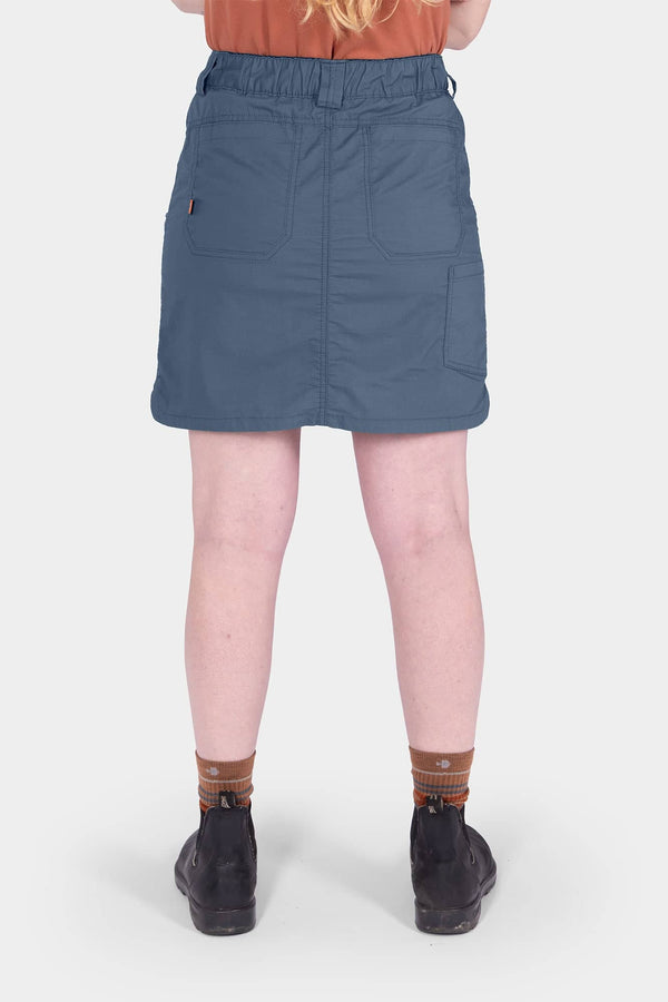 Back view of a woman wearing the Dovetail Workwear Compass COOLSWAP™ Cargo Skort in Dovetail Blue, showcasing the deep inset back pockets and high-rise waistband