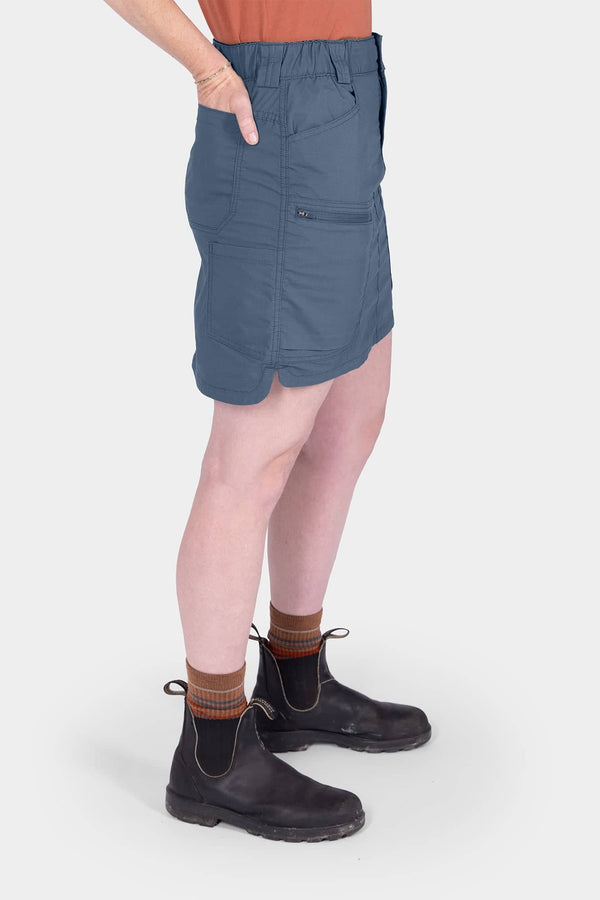 Side view of a woman wearing the Dovetail Blue Compass COOLSWAP™ Cargo Skort in Dovetail Blue, showcasing the cargo pockets and stretch mesh undershorts