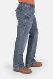 Side view of a woman wearing Dovetail Workwear's Day Construct Work Pant in Vintage Blue denim, showcasing multiple pockets and reinforced knee pad slots