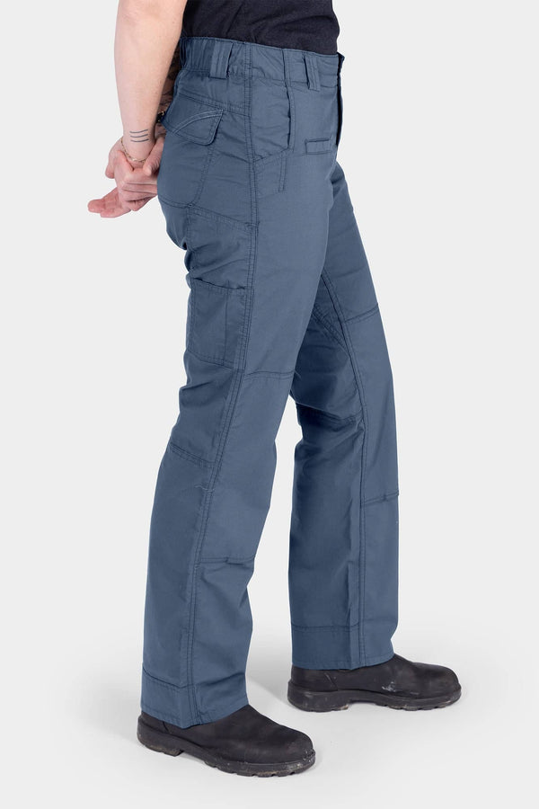 Side view of a woman wearing the Dovetail Workwear Day X COOLSWAP™ Pant in Dovetail Blue, showcasing the relaxed leg fit, multiple pockets, and reinforced knee design