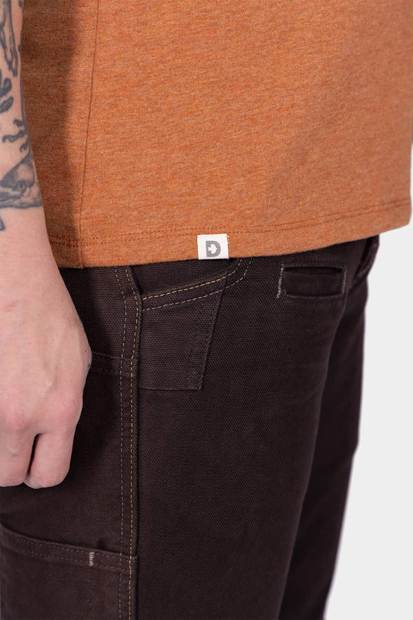 Detail view of a woman wearing Dovetail Workwear's GO TO "Get Dirty" Graphic Work Tee, paired with black work pants