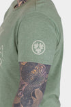 Side view of a woman wearing the Dovetail Workwear GO TO "Work Like a Mother" Graphic Work Tee in sage green with front graphic