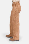 Side view of a woman wearing Dovetail Workwear's Old School Wide Leg Mineral Wash Jeans in Sunbaked Copper, showcasing the high-rise fit and wide leg silhouette with visible tool loop and nested side pocket details