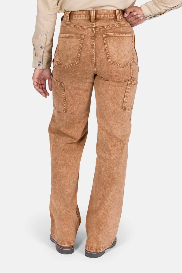 Back view of a woman wearing Dovetail Workwear's Old School Wide Leg Mineral Wash Jeans in Sunbaked Copper, showcasing the high-rise fit, nested side pockets, and wide leg silhouette